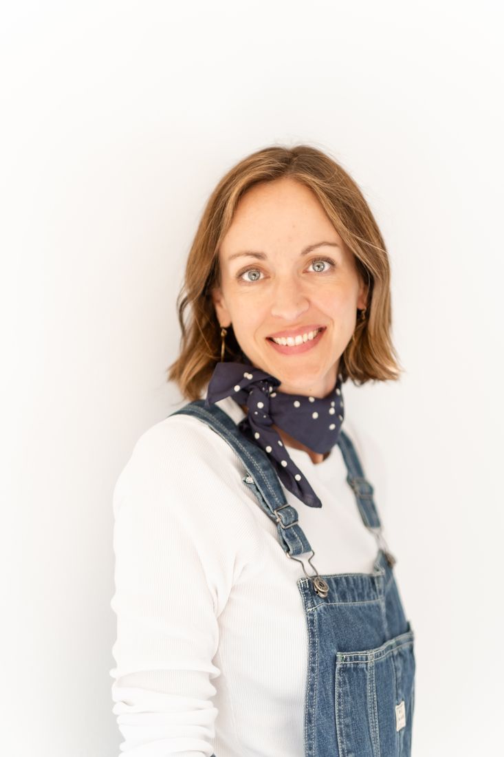 Portrait of Amy smiling in overalls and a polka-dot scarf