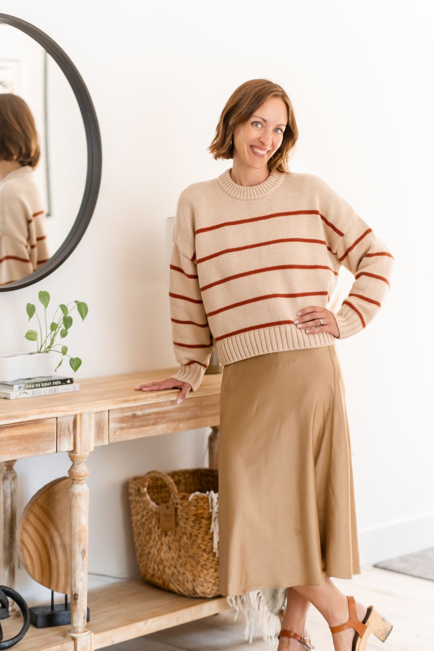 Amy Hyden standing by an entry table in a striped sweater