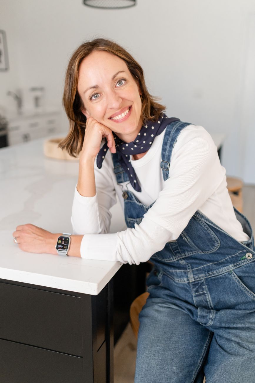 Amy Hyden smiling at a kitchen island in denim overalls