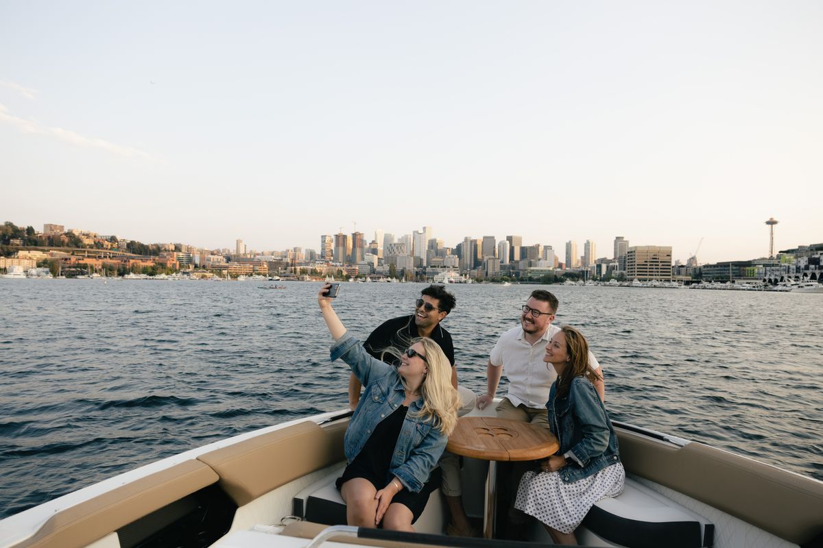 Friends taking a selfie on a boat with the Seattle skyline behind