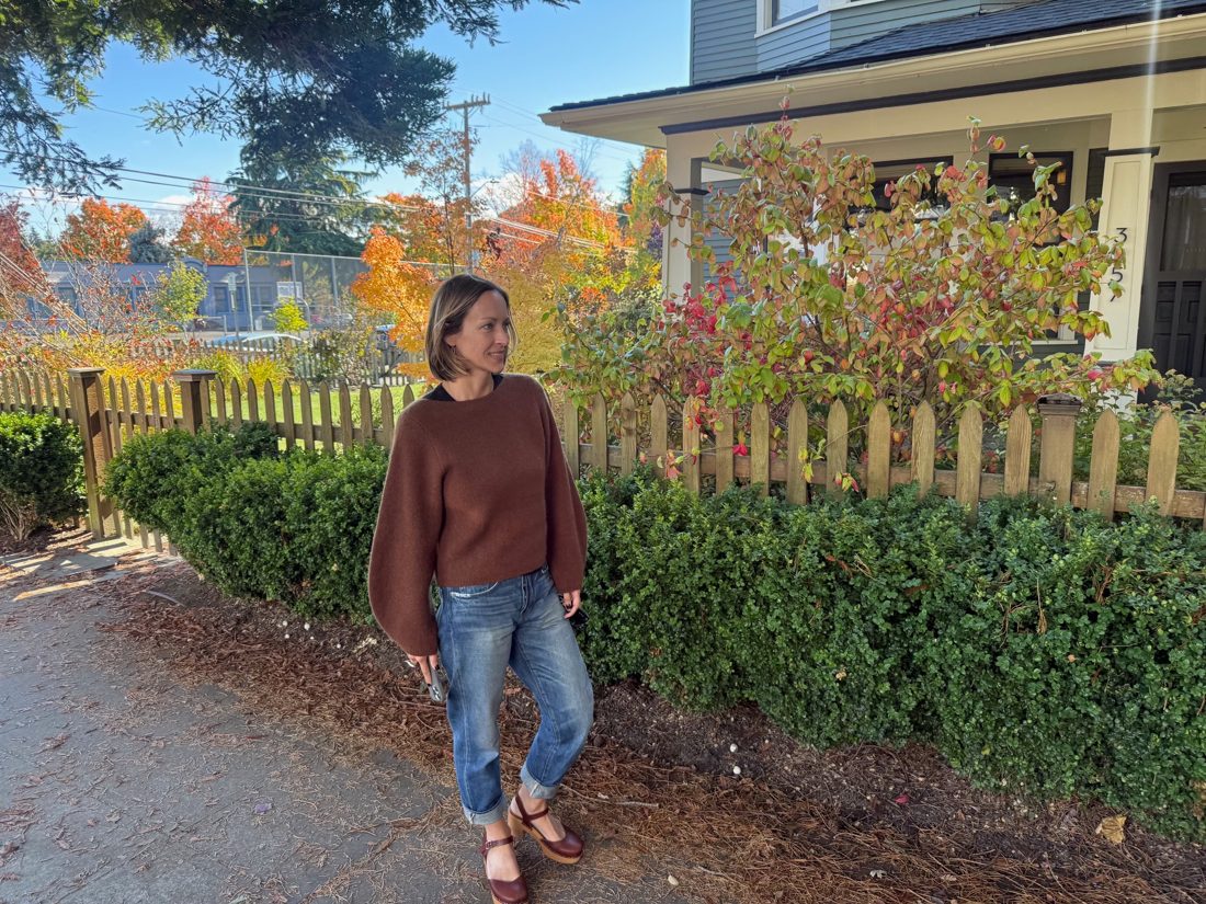 Amy Hyden walking past a picket fence on a sunny fall day in Columbia City