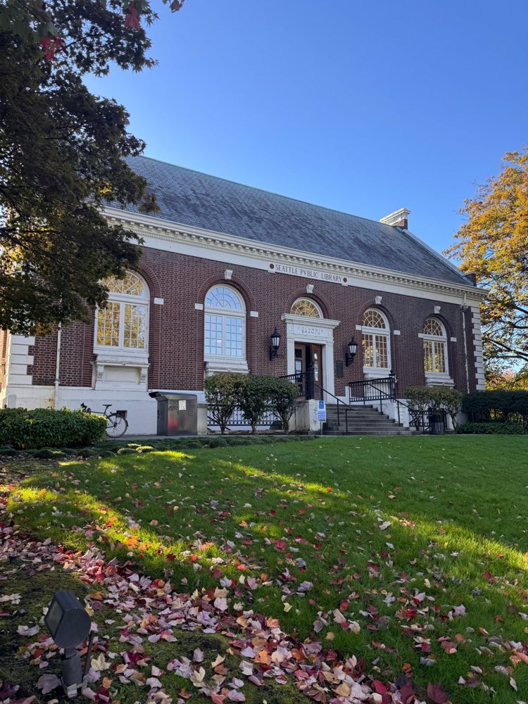 The brick Columbia branch of the Seattle Public Library, with fall leaves on the lawn