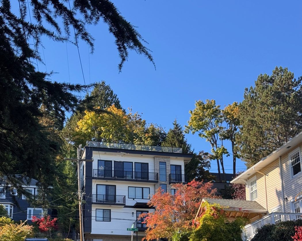 A modern four-story home with balconies on a sloping street