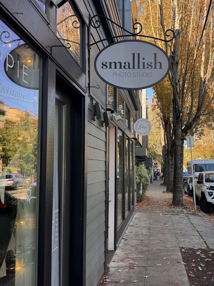 The hanging sign for Smallish Photo Studio on a leafy 34th Ave sidewalk