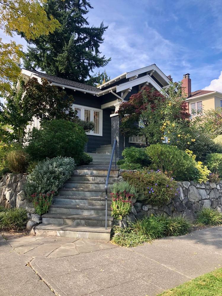 A Craftsman bungalow with stone steps and a rock garden wall in Mount Baker