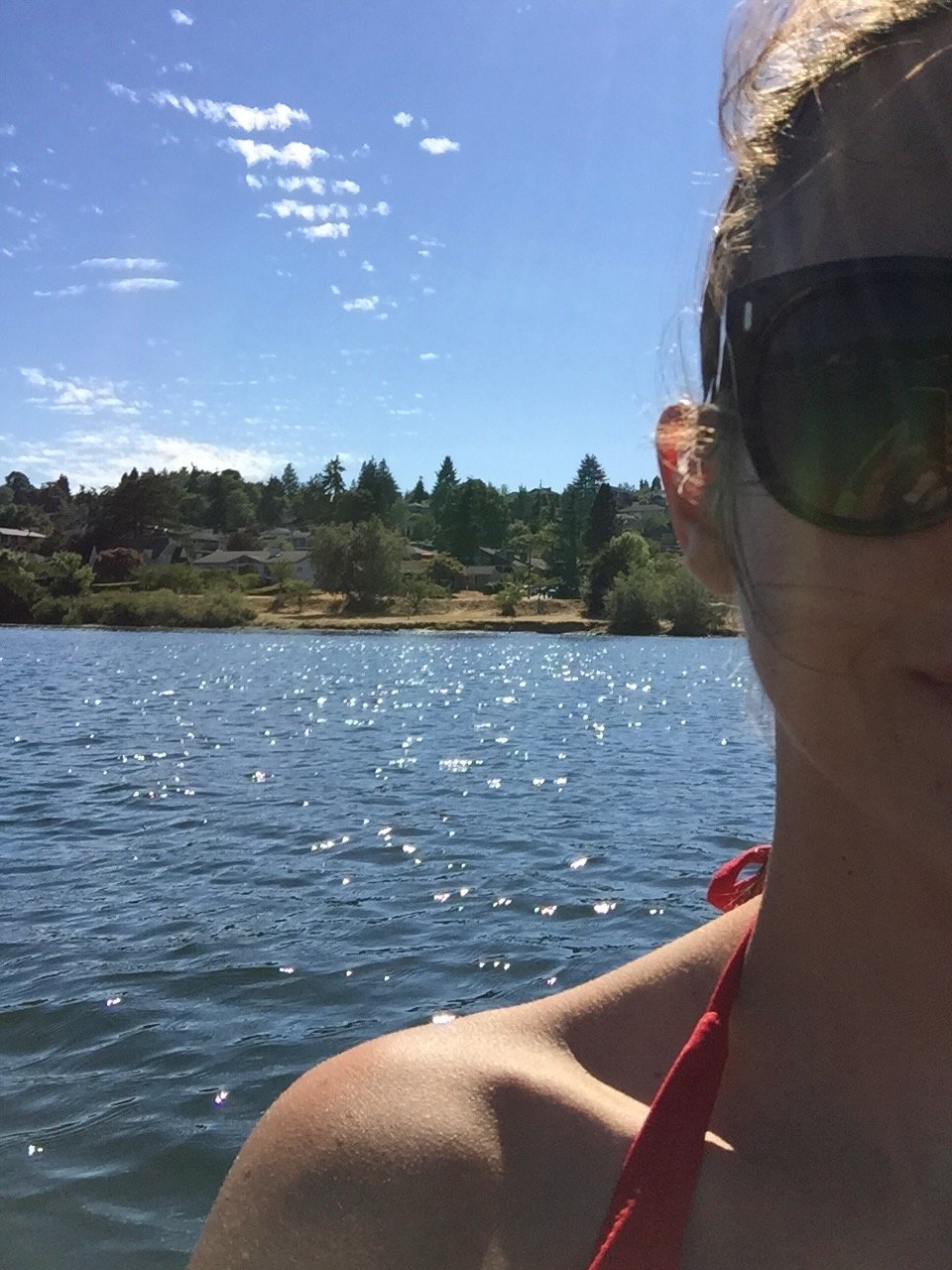 Amy in sunglasses, smiling from a kayak on Lake Washington