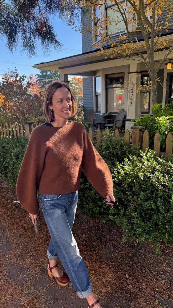 Amy Hyden walking past a picket fence on a sunny fall day