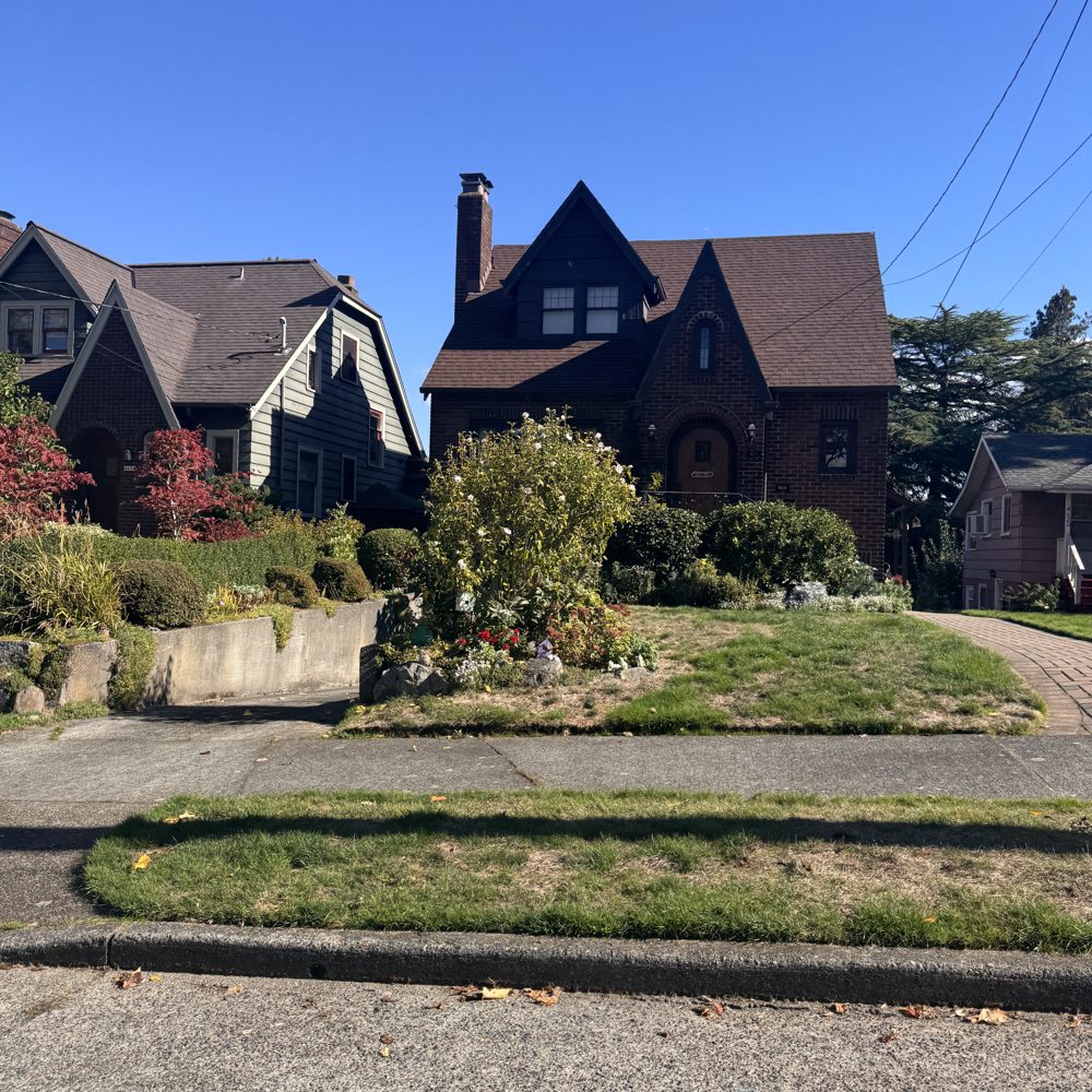 Two brick Tudor homes with steep gables and a terraced garden