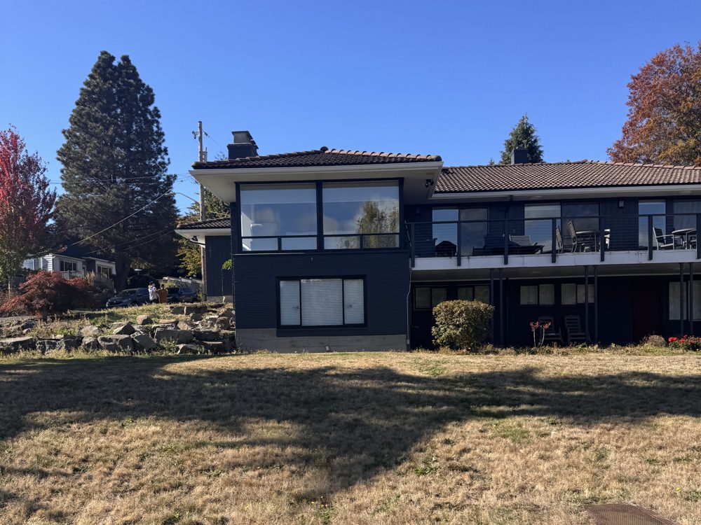 A mid-century home with wide windows above a lawn near Lake Washington