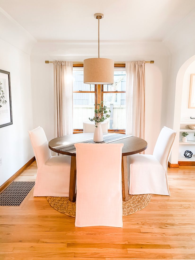 A bright dining room with a round table under a pendant light