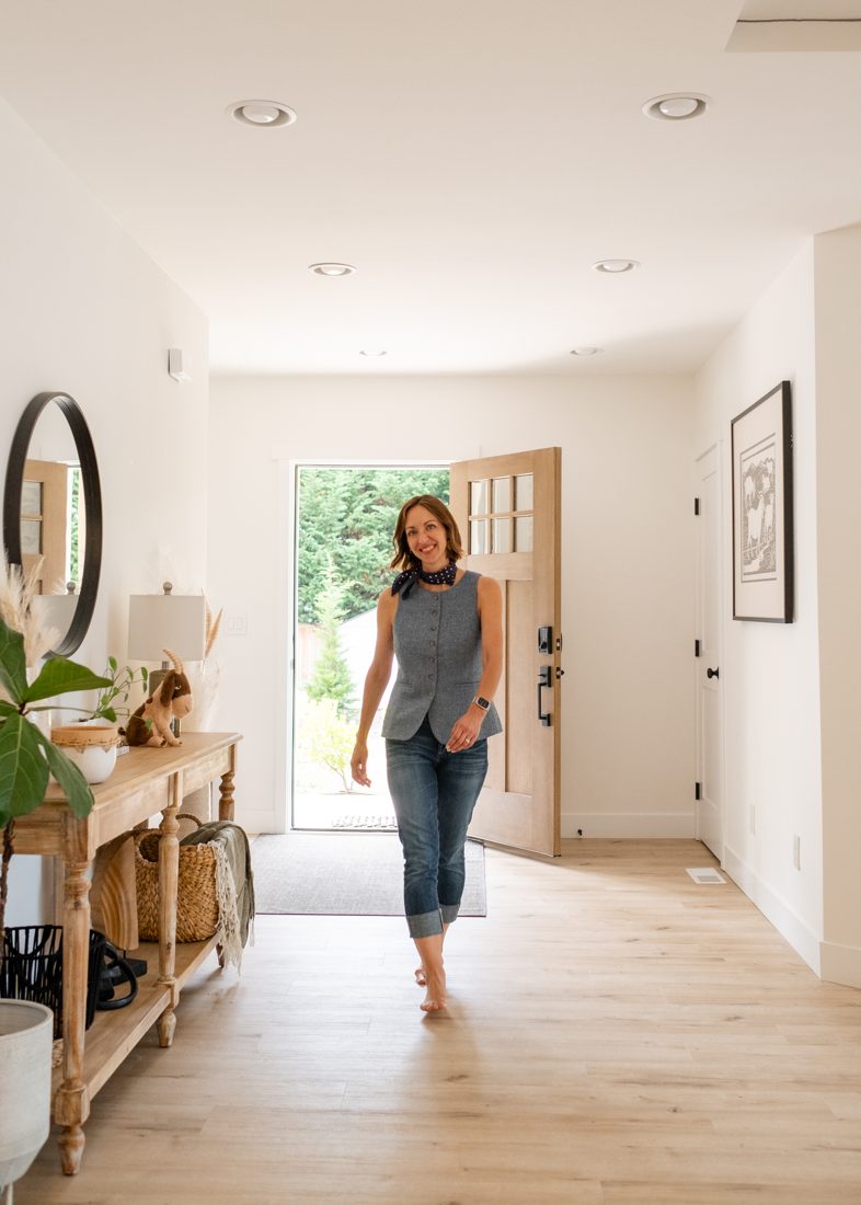 Amy smiling as she walks in through the front door of a bright home