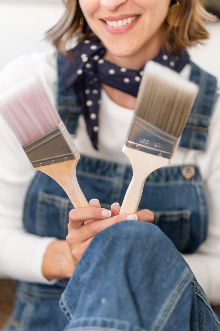 Amy smiling and holding up two paintbrushes